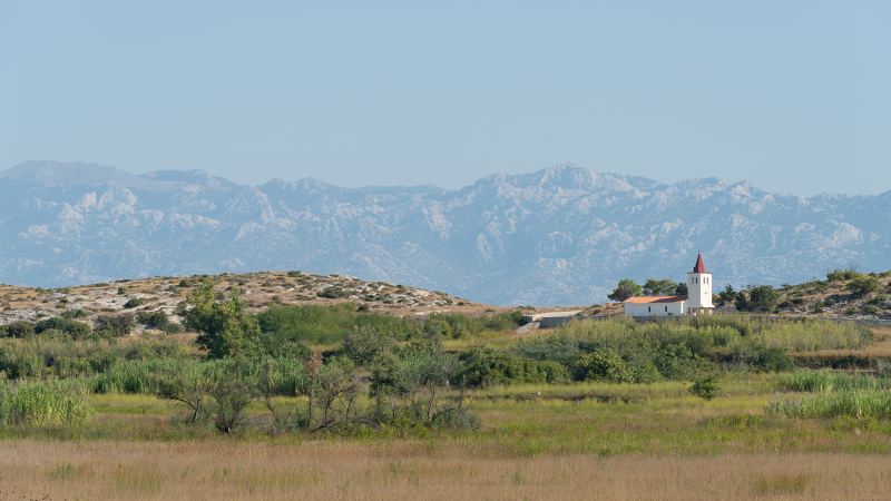 Weiße Kapelle mit rotem Turm vor dem Velebit-Gebirge – Villa DEA in Vrsi-Mulo bei Zadar
