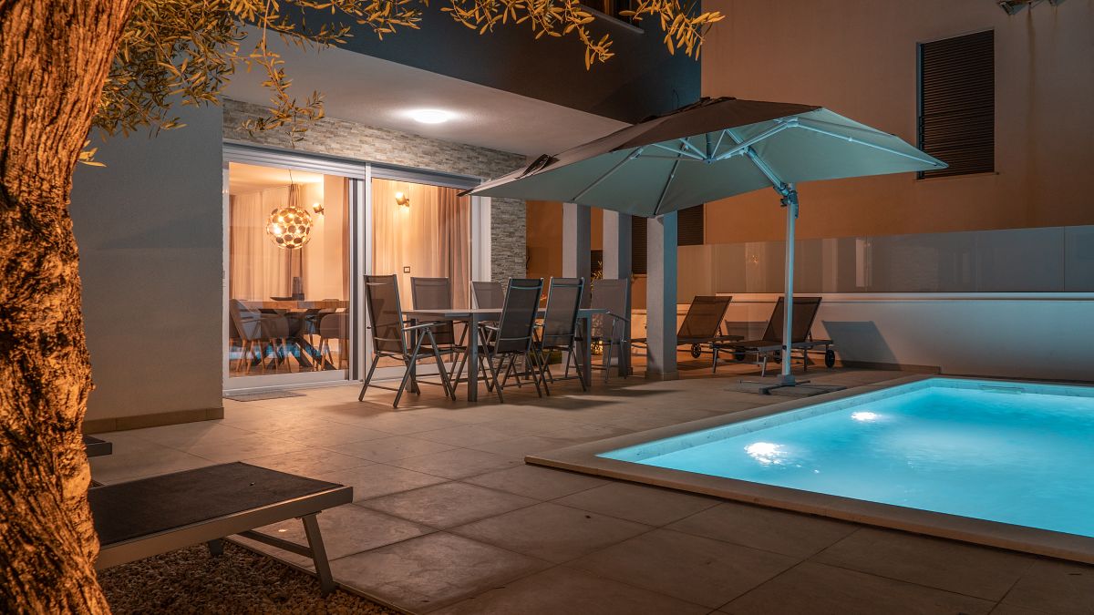Ferienhaus DEA 1 mit Terrasse und beleuchtetem Pool am Abend in Vrsi-Mulo bei Zadar